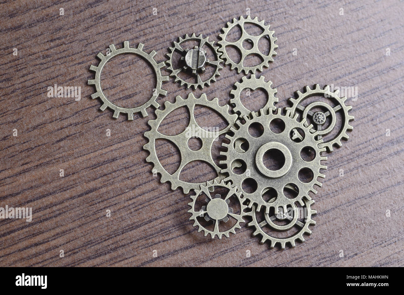 Cogs, Wheels and Gears against a wooden background. Stock Photo