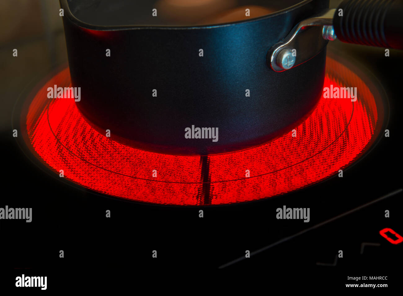 Saucepan on a glowing electric ceramic cooking hob Stock Photo