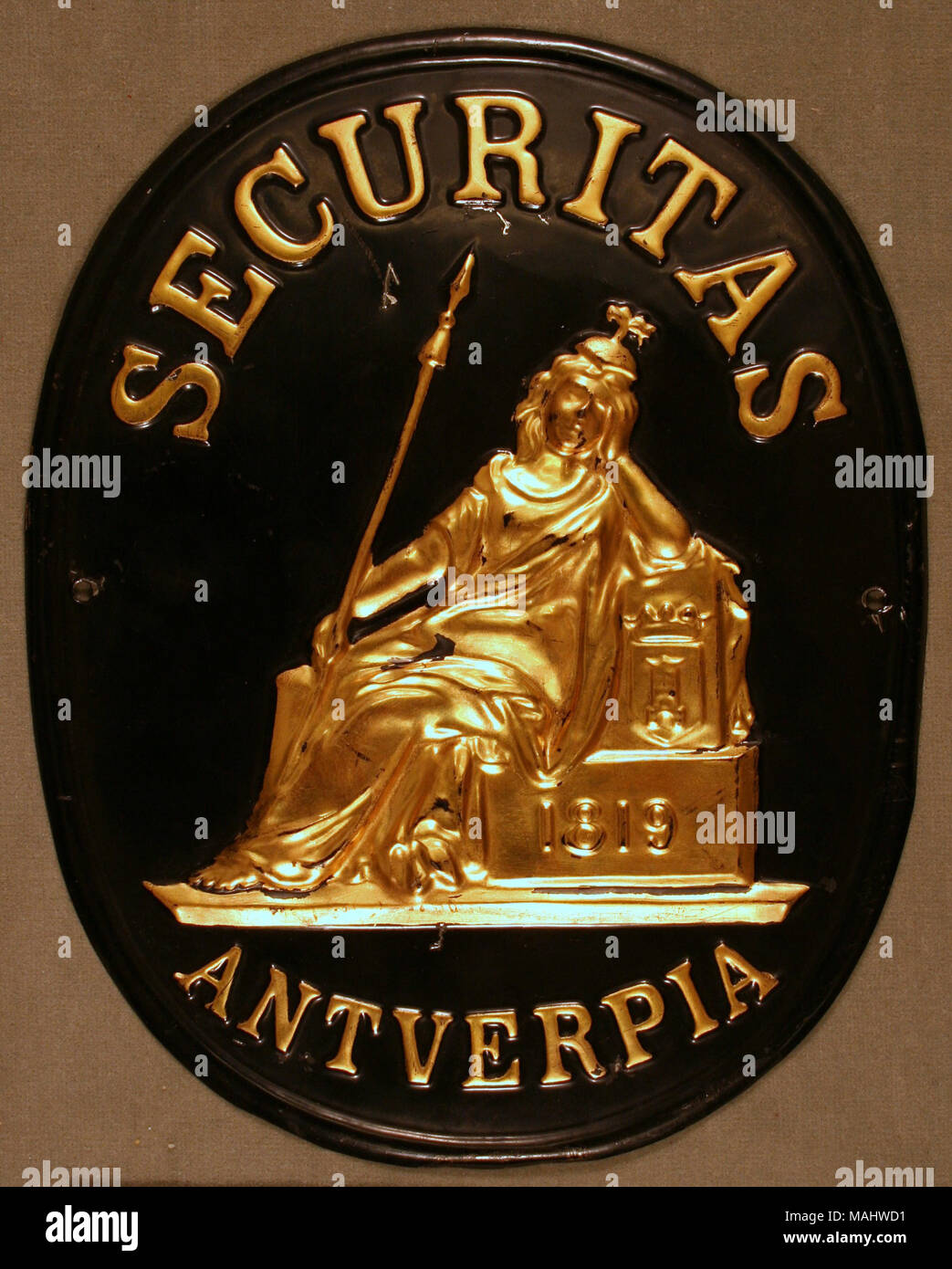 Pressed tin fire mark for the Compagnie d'Assurance d'Anvers Securitas Societe Anonyme in Antwerp, Belgium shows seated gold figure raised on black background in center with gold lettering Title: Fire mark for the Compagnie d'Assurance d'Anvers Securitas Societe Anonyme in Antwerp, Belgium  . after 1819. Stock Photo