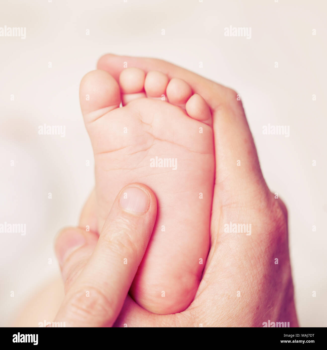 Male hand with baby feet, parental care Stock Photo