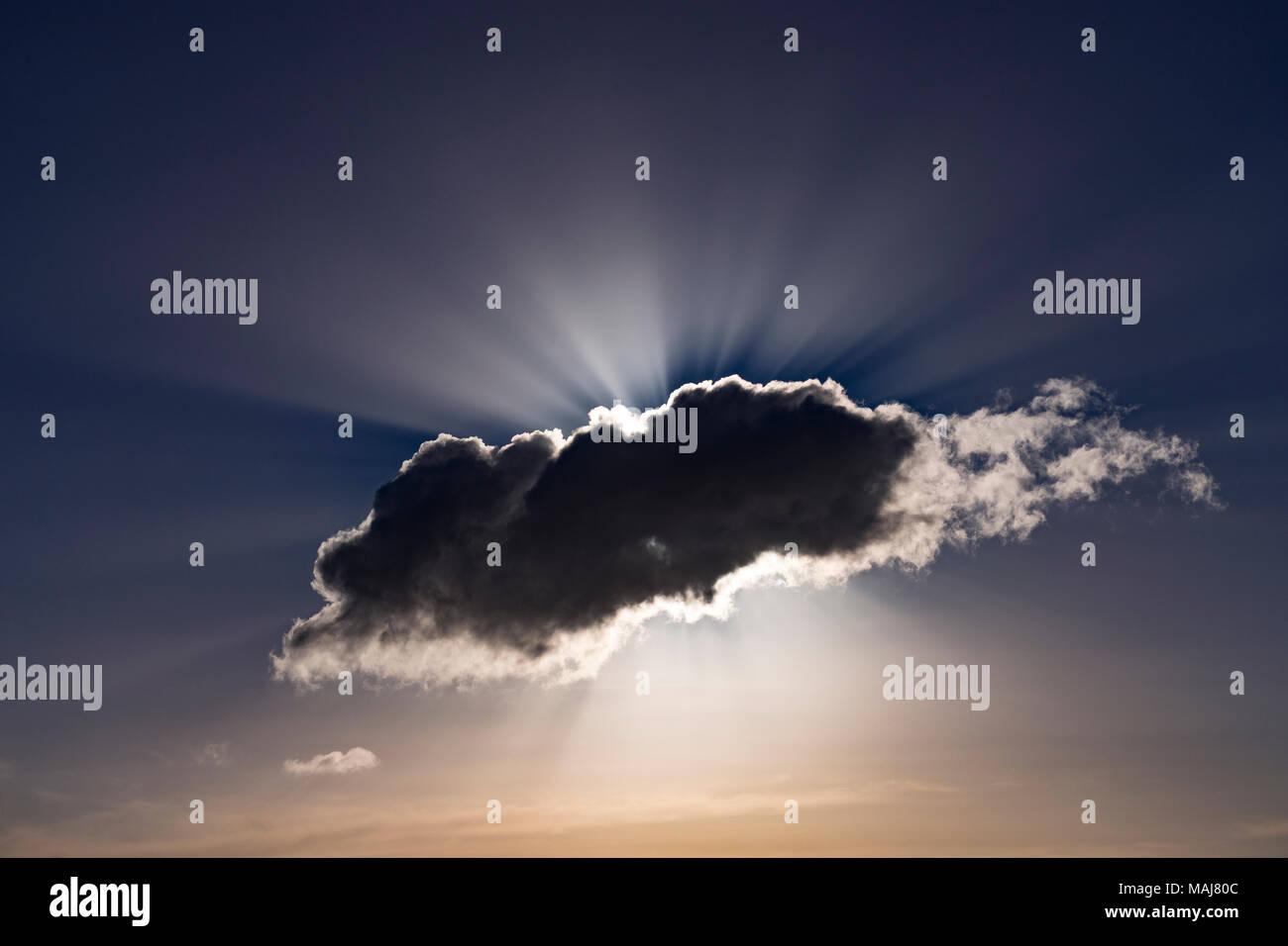 Sunrays bursting from behind a dark cumulus cloud Stock Photo