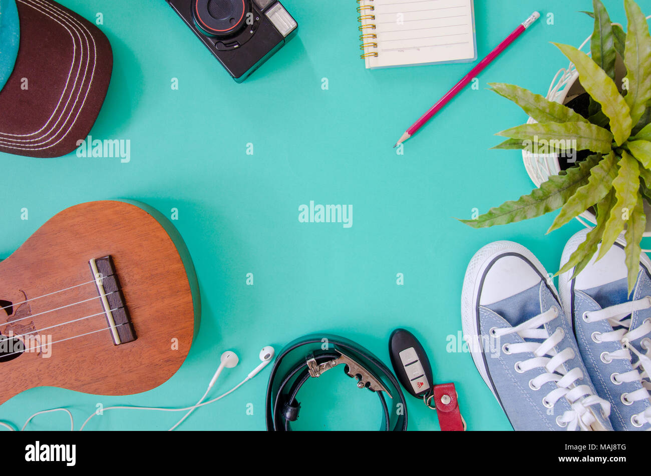 Traveler accessories. Shoes, , ukulele, pencils and notebooks  and phone on the green background. Stock Photo