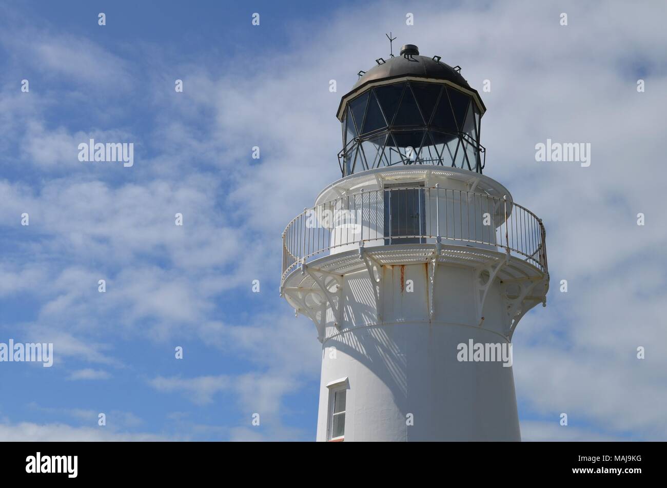 white lighthouse in front of blue sky and some clouds Stock Photo