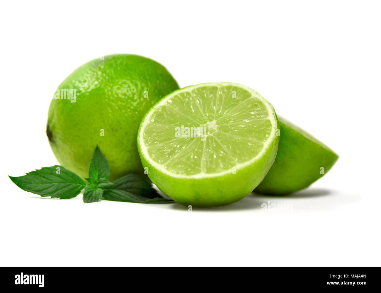 Fresh limes, isolated on white background. Cross section and whole lime fruits with mint leaf, citrus fruit background. Stock Photo