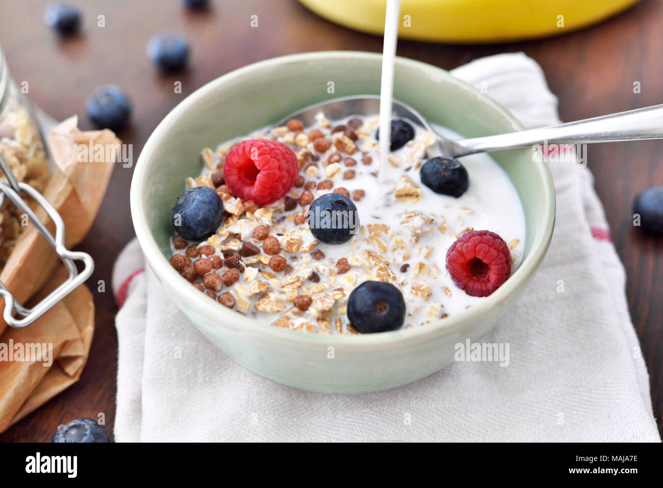 Cereals in a bowl, breakfast scene with fresh fruits and muesli, healthy eating. Breakfast bowl on a wooden table, rustic scene. Stock Photo