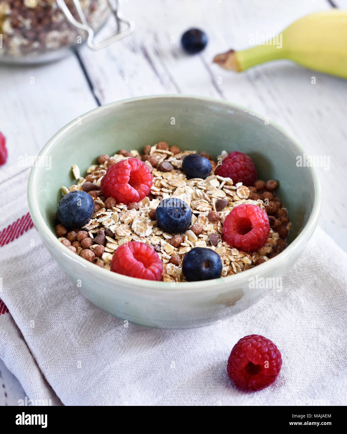 Cereals in a bowl, breakfast scene with fresh fruits and muesli, healthy eating. Breakfast bowl on a wooden table, rustic scene. Stock Photo