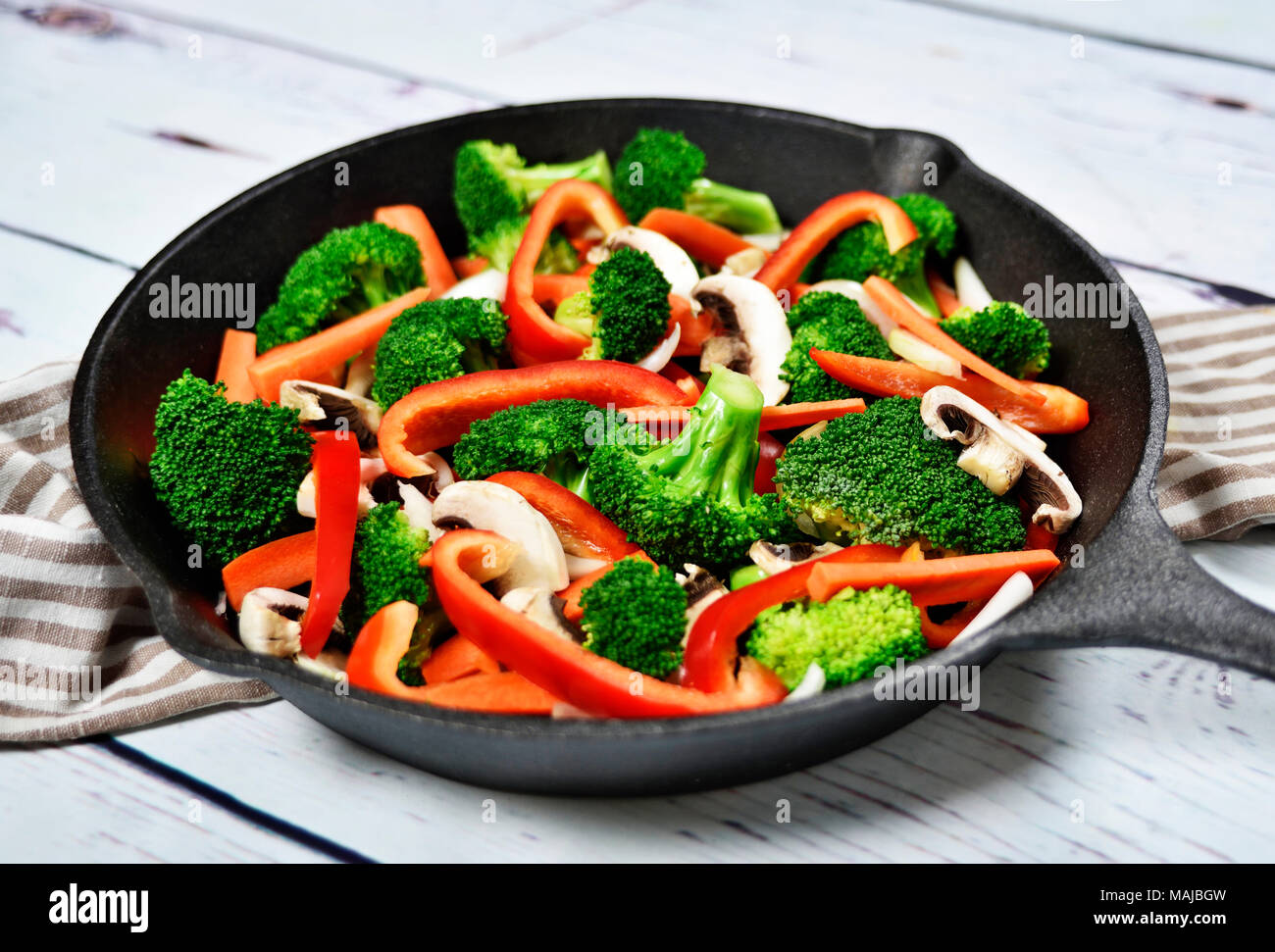 Healthy eating scene with vegetables in an iron pan or cooking pan. Broccoli, red bell pepper, carrots and white mushrooms. Stock Photo
