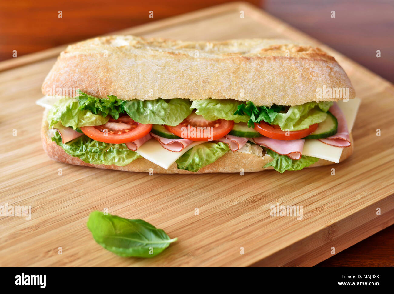 Ciabatta sandwich or club sandwich with ciabatta baguette and various ingredients. ham and cheese baguette with fresh tomatoes and salad. Stock Photo