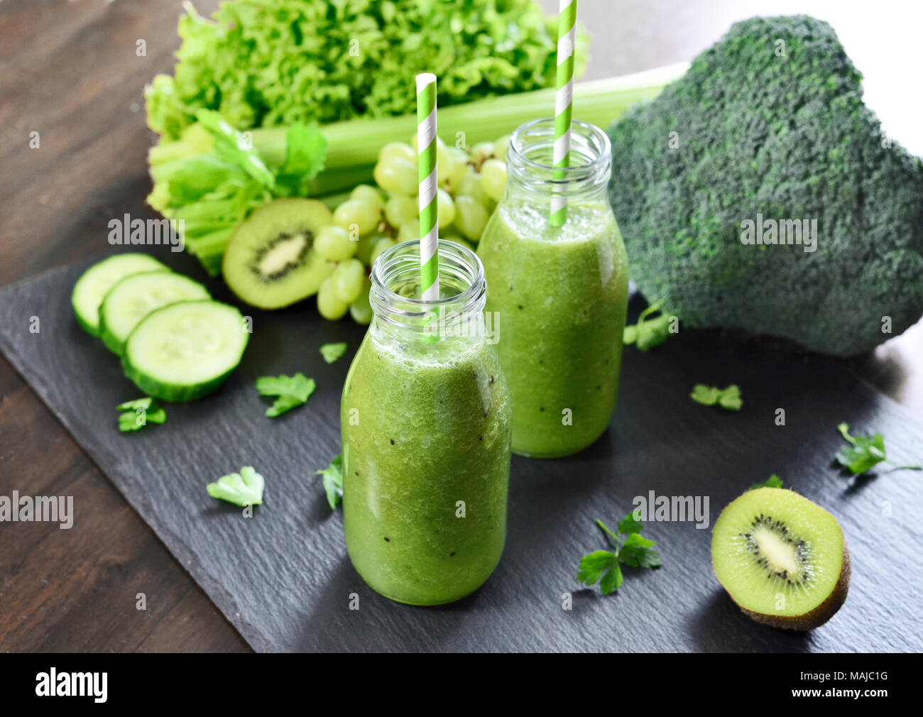 Green smoothie in drinking glasses. Fitness or dieting drink with kiwi, broccoli, lettuce and various ingredients. Healthy drink in a glass bottle. Stock Photo