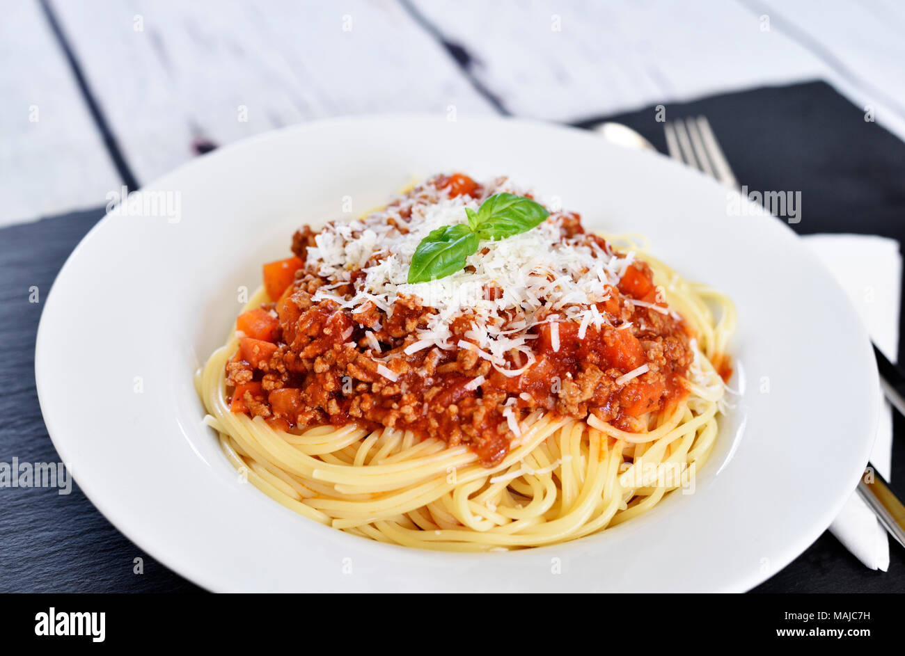 Delicious pasta meal, spaghetti bolognese on a white plate. Pasta Dish, traditional italian food with parmesan cheese, minced meat and basil leaf. Stock Photo
