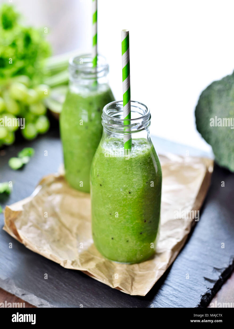 Green smoothie in drinking glasses. Fitness or dieting drink with kiwi, broccoli, lettuce and various ingredients. Healthy drink in a glass bottle. Stock Photo