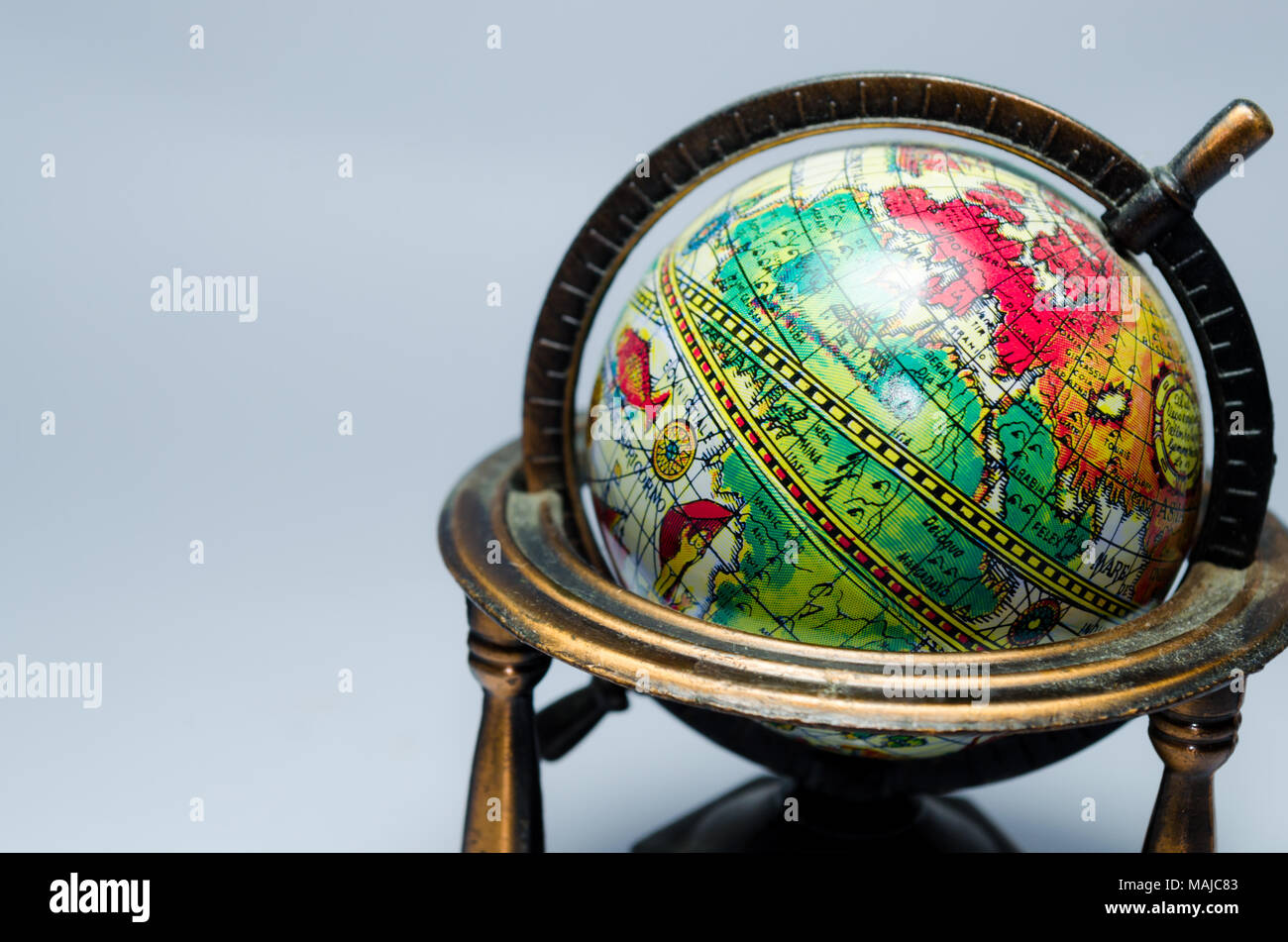 colored mini earth globe in a copper structure referring to navigations, adventures and exploration. Old times. white background and space for caption Stock Photo