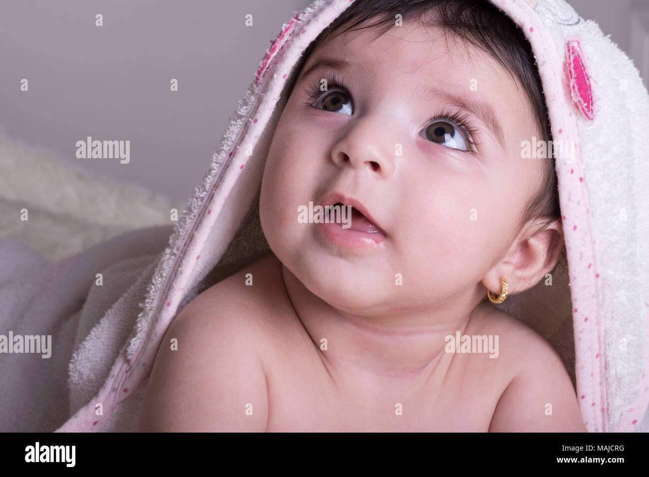 Little baby wearing white bath towel, relaxing in bed after bath or