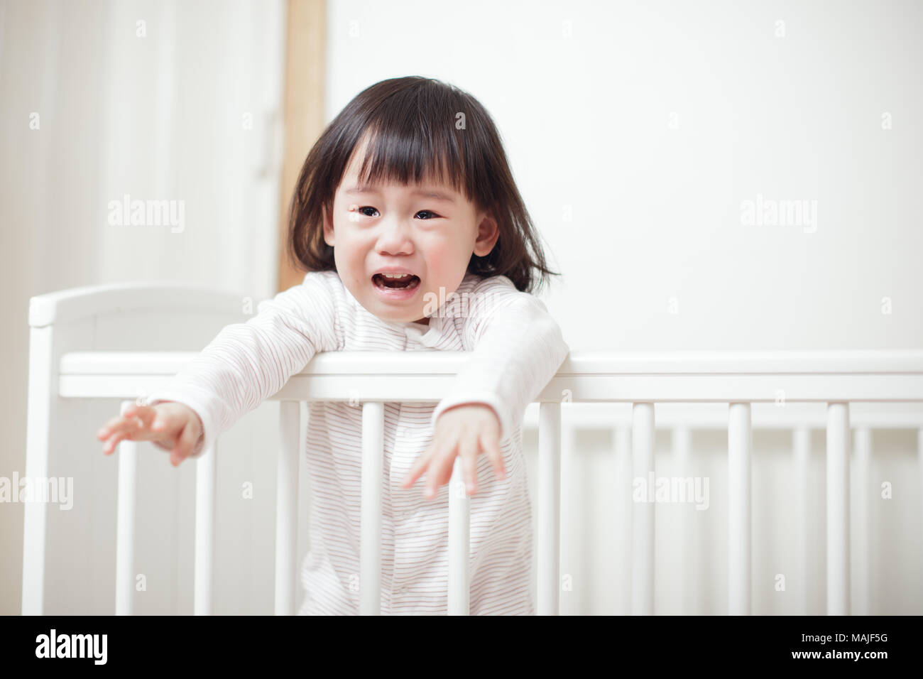 Crying Baby girl in cot bed Stock Photo Alamy