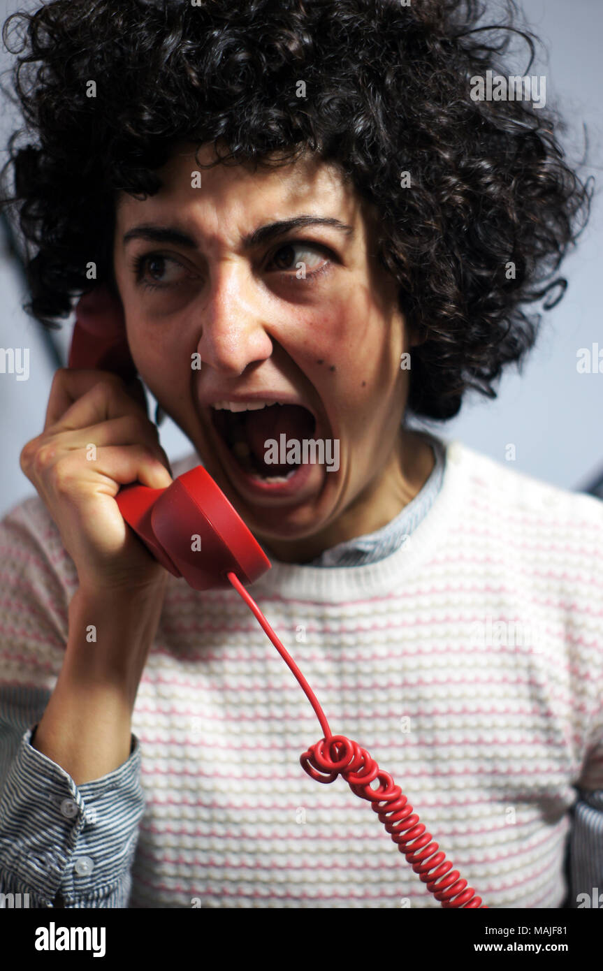 Woman is going mad on red phone Stock Photo