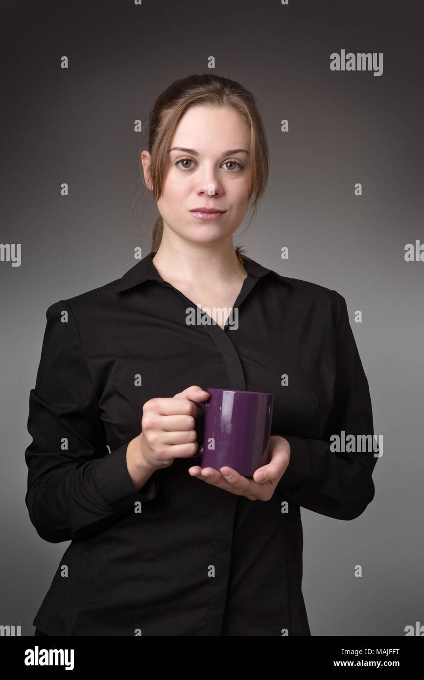 young standing business woman shot in the studio on a grey background ...