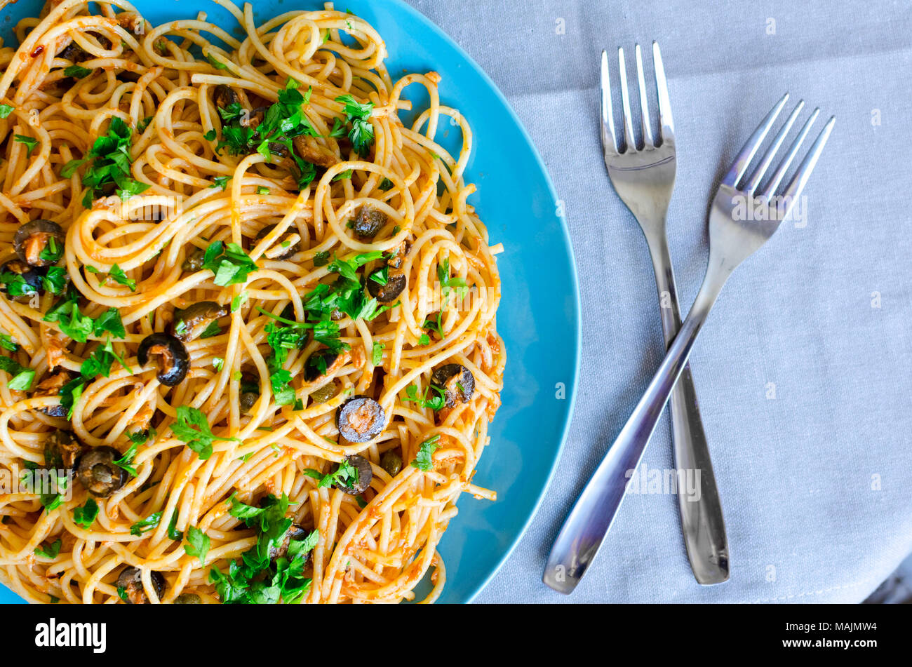 Spaghetti Alla Puttanesca - traditional italian pasta with black olives, tuna, anchovies, capers and parsley. Vegetarian food. Italian cuisine. Top vi Stock Photo