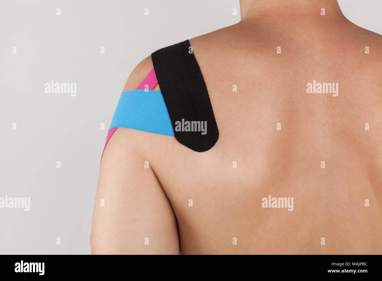 Physiotherapy therapeutic taping on man shoulder isolated on grey