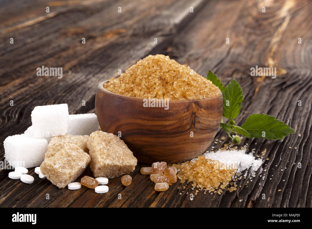 Various types of sugar, brown sugar, white sugar, crystal sugar, artificial sweetener, cane sugar and aztec sweet herb on wooden table. Stock Photo