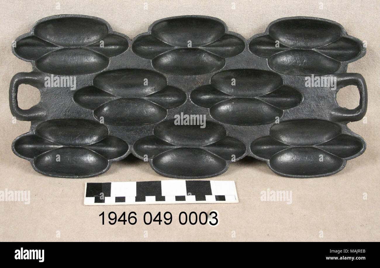 Unique form of cast iron muffin pan has 8 concave detailed sections; made by St. Louis company G.F. Filley Title: Oblong cast iron muffin pan  . circa 1880. Excelsior Stove and Manufacturing Co. Stock Photo
