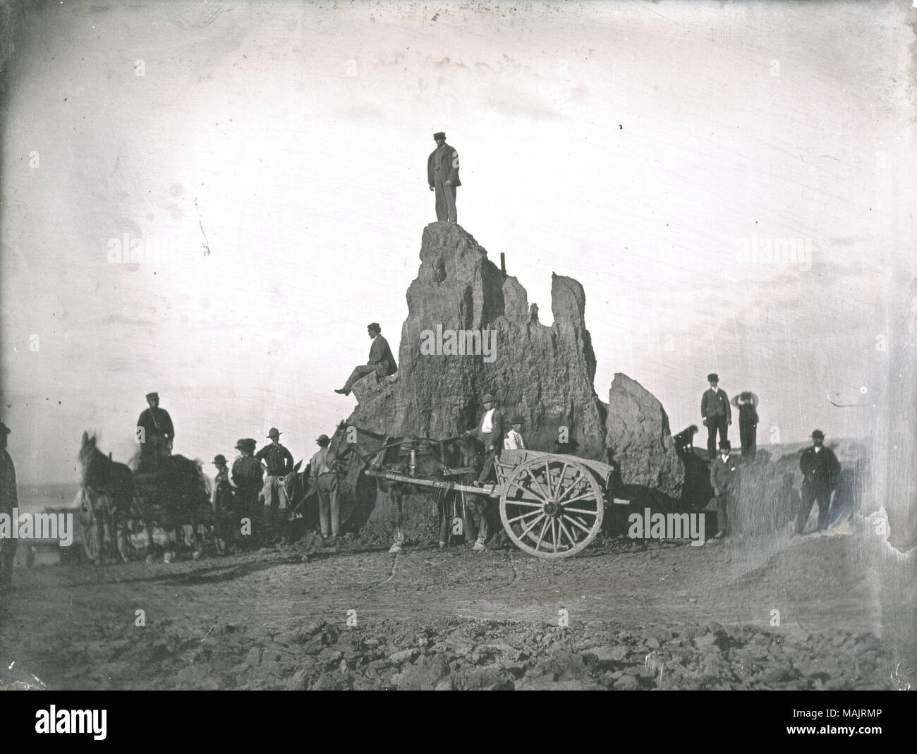 Men, boys, a dog, and a horse with a wagon stand on top of and in front of the Big Mound during its destruction. This is the last of the Big Mound; only a sliver of the original mound remains. A pole is stuck into the mound near the top and a shovel leans up against one man standing on the right of the daguerreotype. Title: Big Mound during destruction. The last of the Big Mound.  . 1869. Thomas M. Easterly Stock Photo