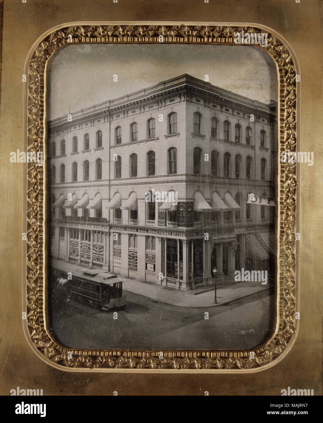 The Ann Lucas Hunt Building on the northwest corner of Fourth and Olive Streets. The architect for the building was Major Francis D. Lee. A streetlamps stands on the corner and a horse-drawn streetcar stands in the street in front of the structure. Signs on the second floor of the building read 'Missouri Mutual Life Insurance Company' and 'Office - St. Louis Fair Grounds'. On the first floor, a sign reads '... Pacific Despatch via Kansas Pacific Railway' and 'General Union Rail Road Ticket Office'. In the windows the following advertisements can be seen: 'Erie and Pacific Despatch via North Mi Stock Photo