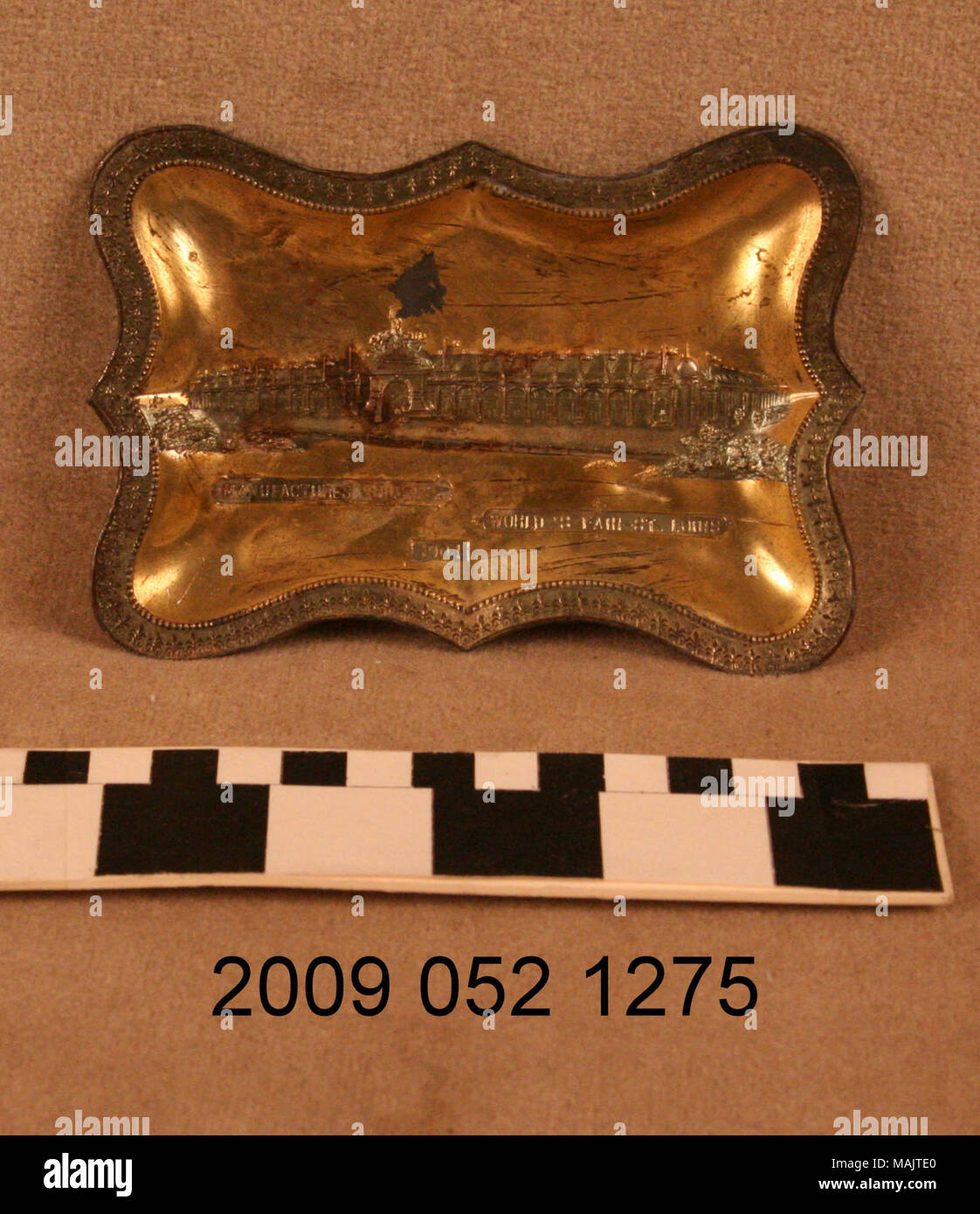 Gold colored pin tray has very scalloped edge with raised image of the Palace of Manufactures from the 1904 World's Fair. Title: Gold Colored Pin Tray With Relief Image of the Palace of Manufactures  . 1904. Stock Photo