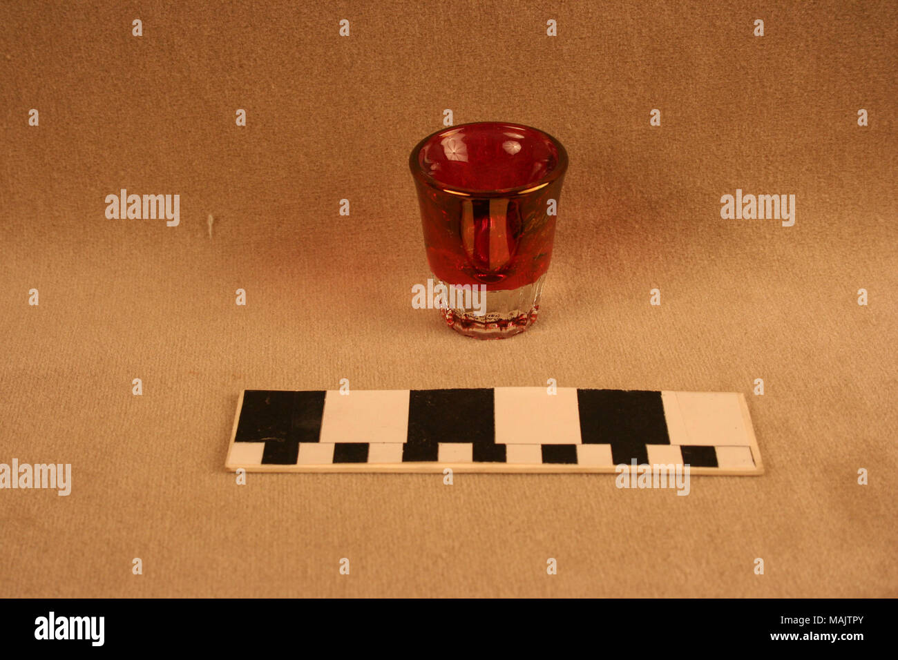 Ruby stained and pressed glass shot glass has nail pattern on lower half. This souvenir is from the 1904 World's Fair. Title: Ruby Stained Shot Glass With Pressed Nail Pattern  . 1904. Stock Photo