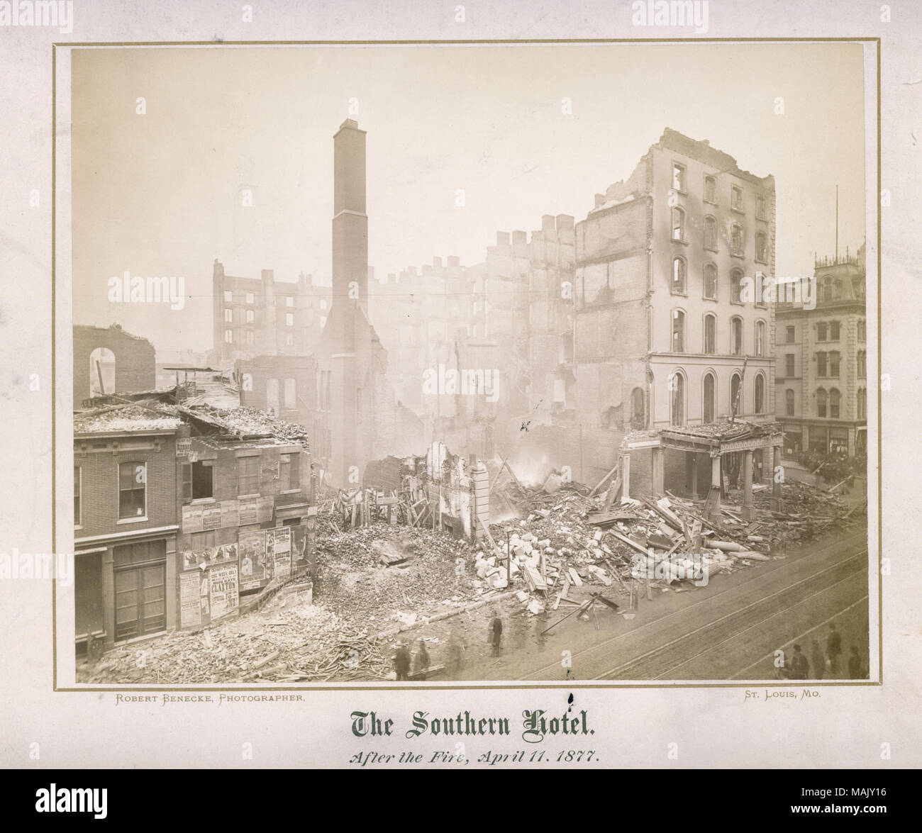 horizontal photo showing a bird's eye view of the remaining shell of a building destroyed by fire. There is rubble in the street and on an adjacent building and the ruins are still smoking. Title: 'The Southern Hotel after the fire, 11 April 1877.'  . April 1877. Robert Benecke Stock Photo