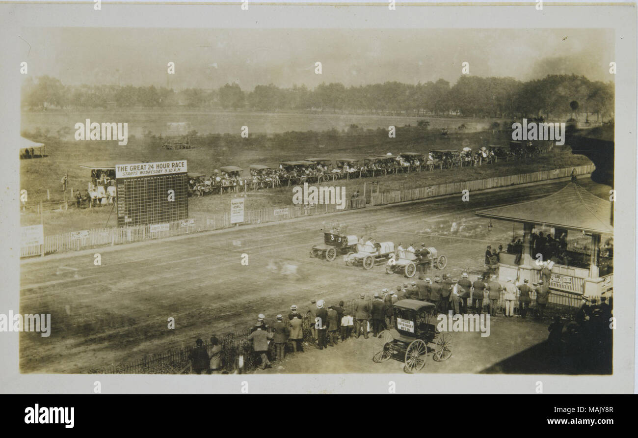 Title: Spectators watching as automobiles line up to race during or shortly before 'The Great 24 Hour Race' at the Fairgrounds Park auto racing track.  . 1907. Stock Photo