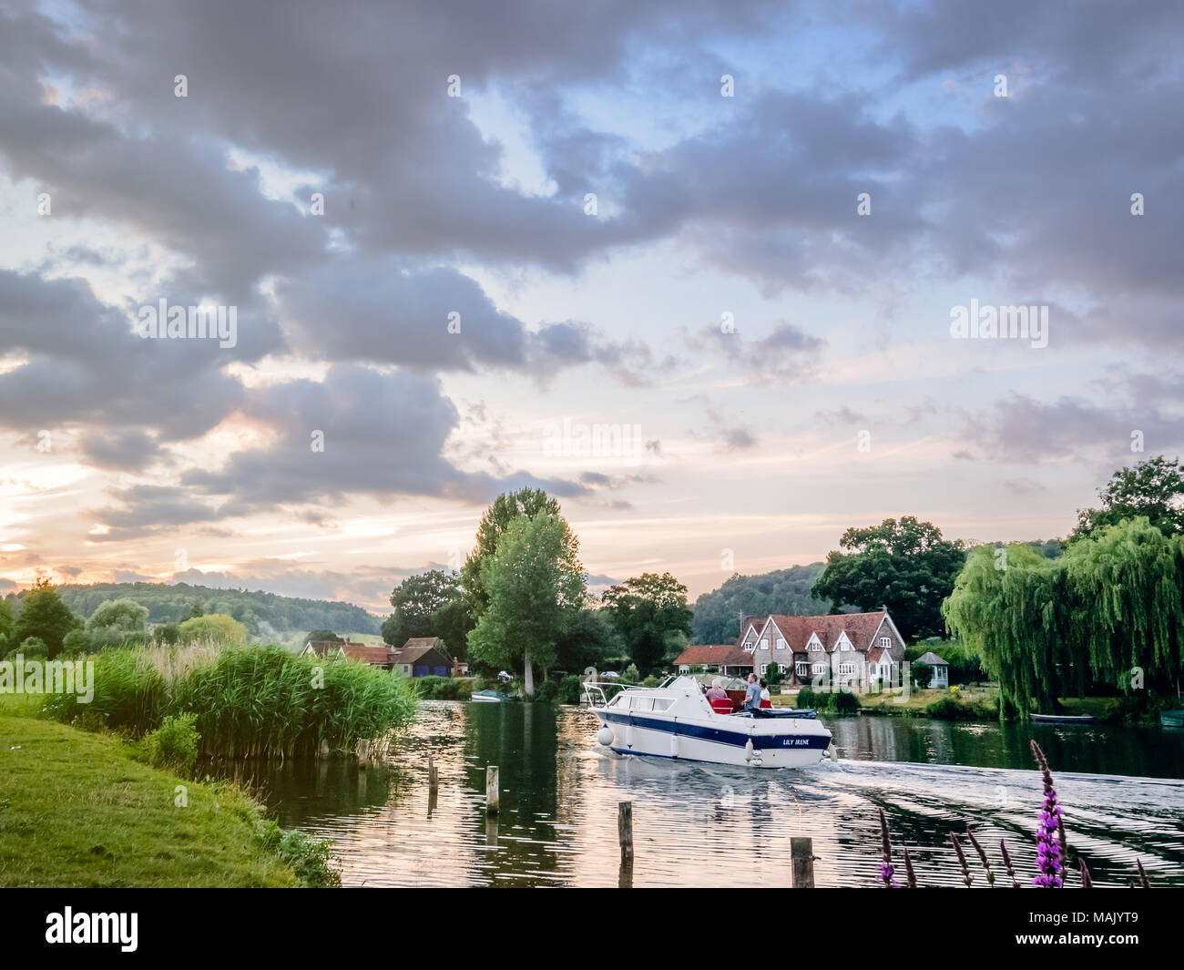 A boat cruises along the Thames in the summer evening light Stock Photo