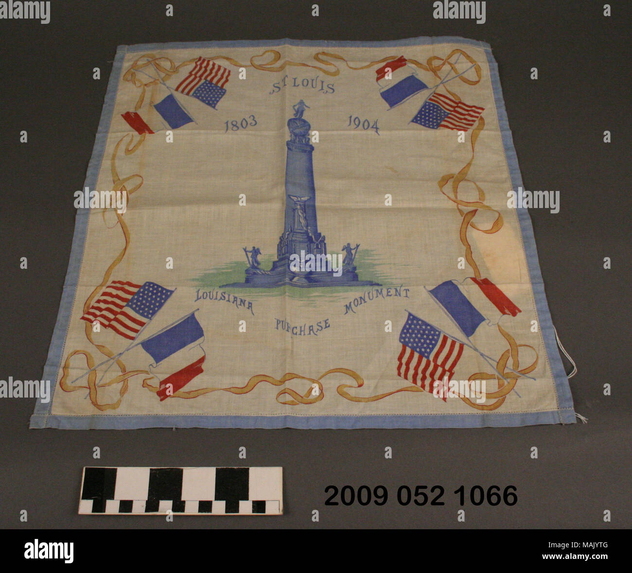 Multi-color cotton scarf has a small, light blue border all around and a large blue rendition of the Louisiana Purchase Monument in the center. It is a souvenir from the 1904 World's Fair. Title: Multi-color Cotton Scarf Featuring the Louisiana Purchase Monument From the 1904 World's Fair  . 1904. Stock Photo