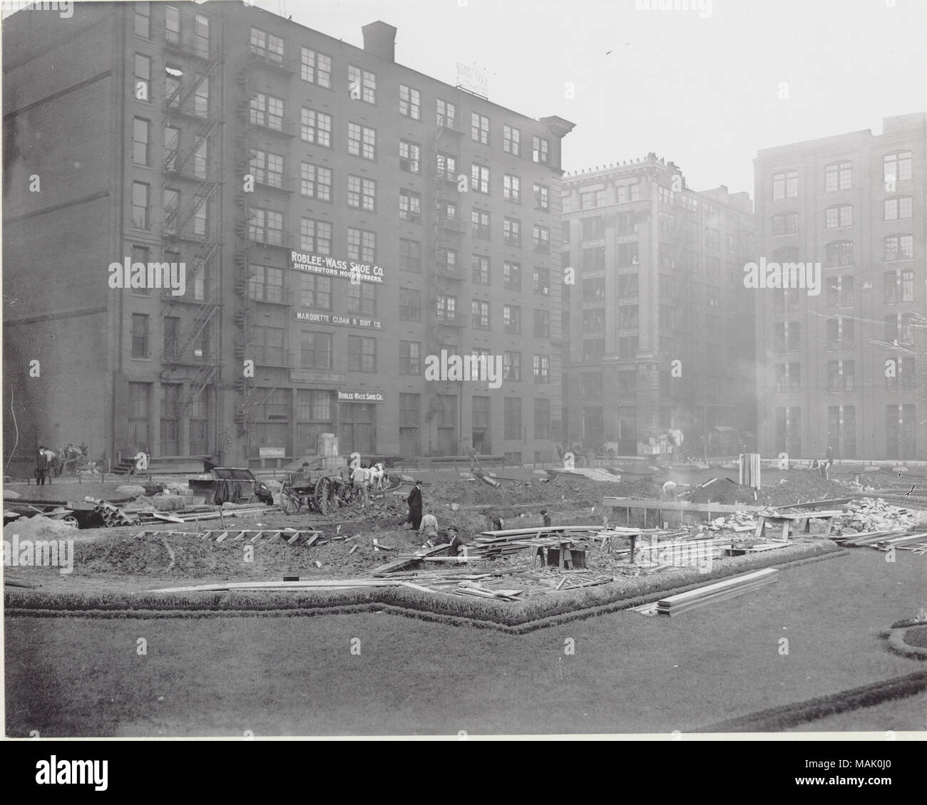 Workers installing a fountain in Lucas Garden. Lucas Garden covered Locust to St. Charles Street and Thirteenth to Fourteenth Streets. View is from Fourteenth and Locust. Lucas Garden was just north of the St. Louis Public Library. The site was originally the estate of Judge John B.C. Lucas, a federal judge who owned much of the land that comprises downtown St. Louis. A spring that provided water to the judge's home still runs through the basement of the St. Louis Public Library just south of Lucas Garden. Title: Workers installing a fountain in Lucas Garden at Fourteenth and Locust Streets.   Stock Photo
