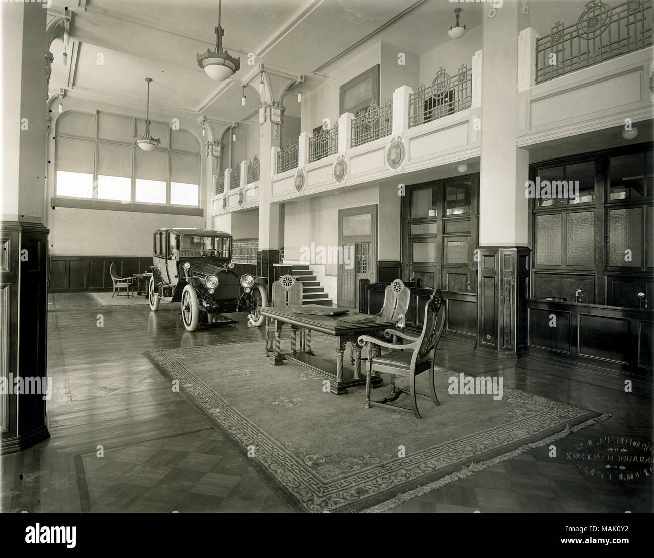 Title: Packard Missouri Motor Company, 2201 Locust Street. Interior view of lobby with mezzanine, showing display automobile next to carpeted area with table and chairs.  . circa 1916. W.C. Persons Stock Photo
