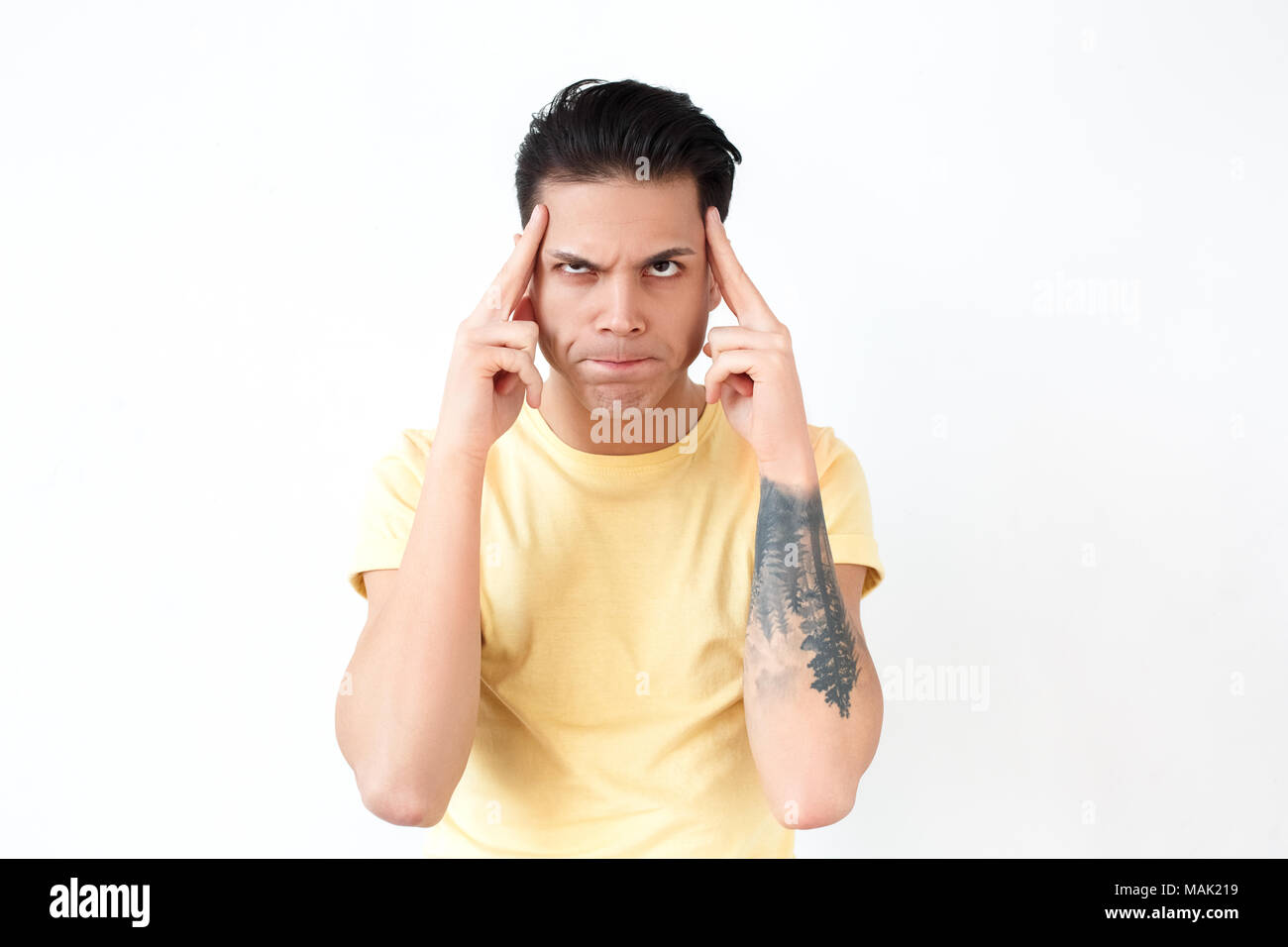 Portrait of clever man, grimacing and wondering. Emotions and feelings concept. Indoor shot, gray background Stock Photo