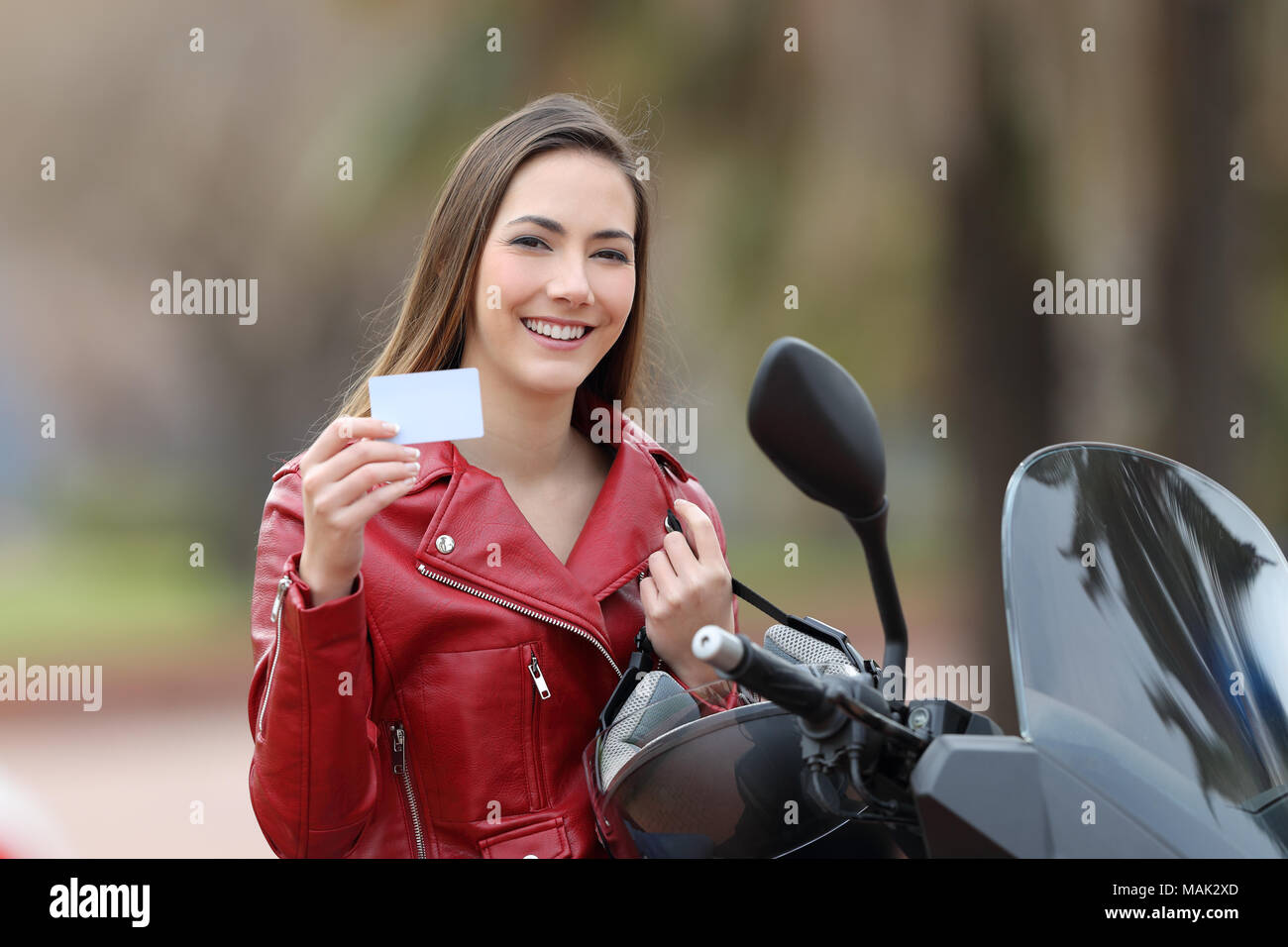 Happy biker girl showing a blank credit card on the street Stock Photo