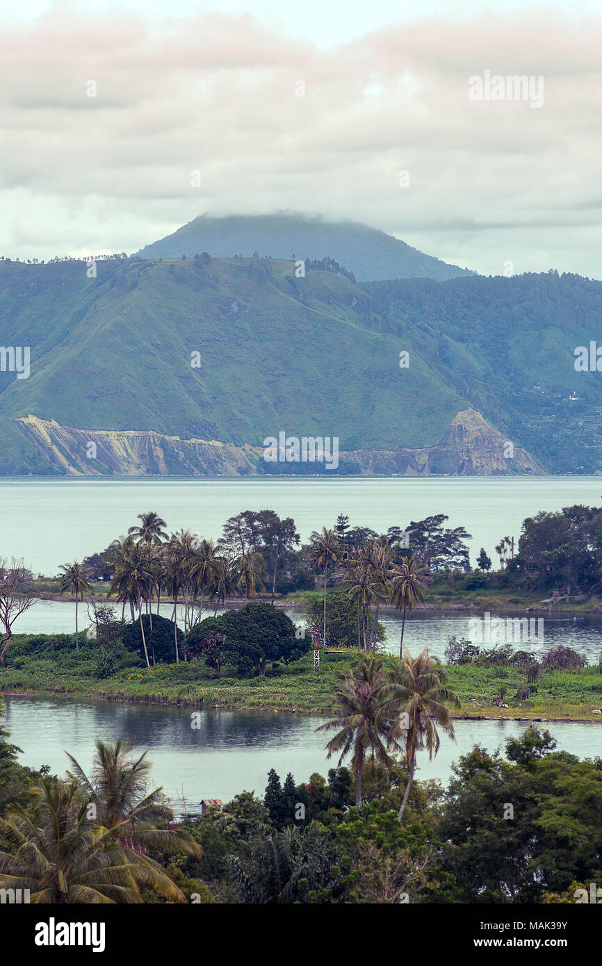 Mt Sinabung with its peak in the clouds viewed from Samosir island across Lake Toba, Sumarta, Indonesia. Stock Photo