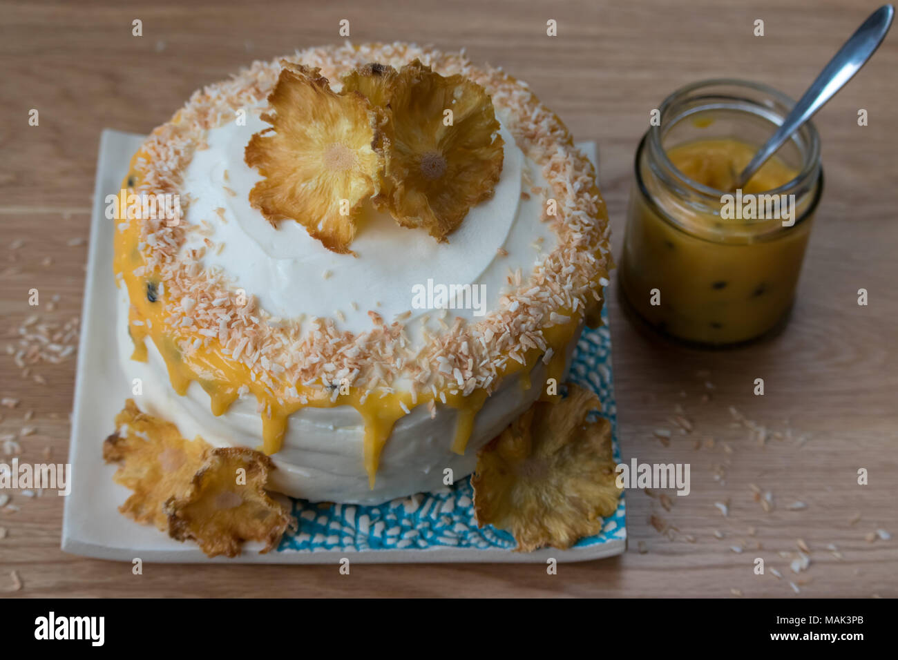A gluten free, pineapple and coconut layer cake with passion fruit curd. Decorated with dried pineapple flowers and displayed on a handmade plate. Stock Photo