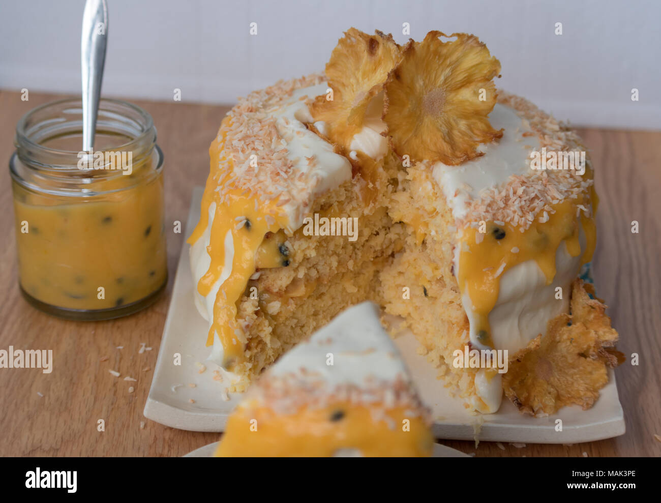 Sliced pineapple and coconut layer cake with passion fruit sauce. Decorated with pineapple flowers. Stock Photo