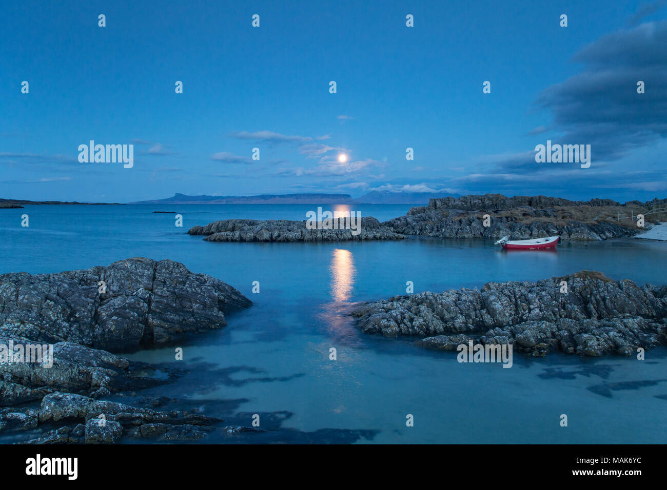 The Island of Rum and Eigg viewed from the West Coast of Scotland, near Arisaig just before dawn with the moon about to disappear behind the islands. Stock Photo