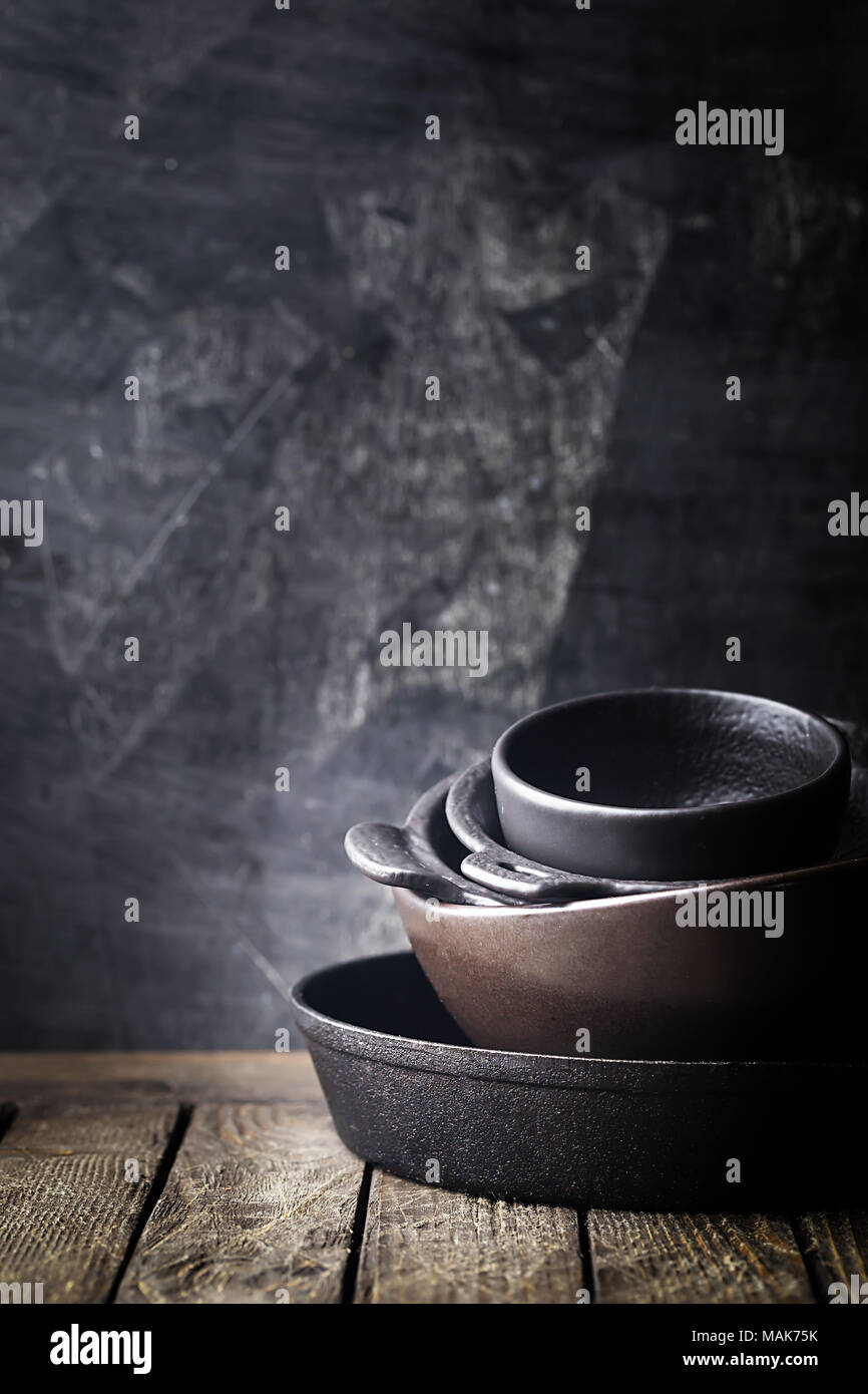 Stack of cast iron cookware over dark background Stock Photo - Alamy