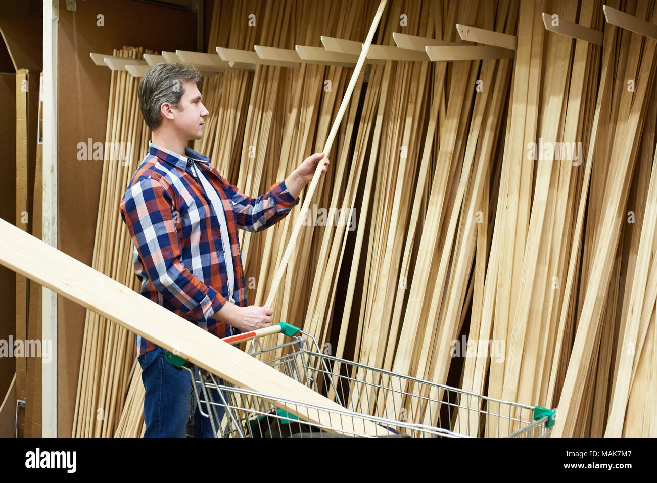 Man chooses and buys wooden boards in a construction supermarket Stock Photo
