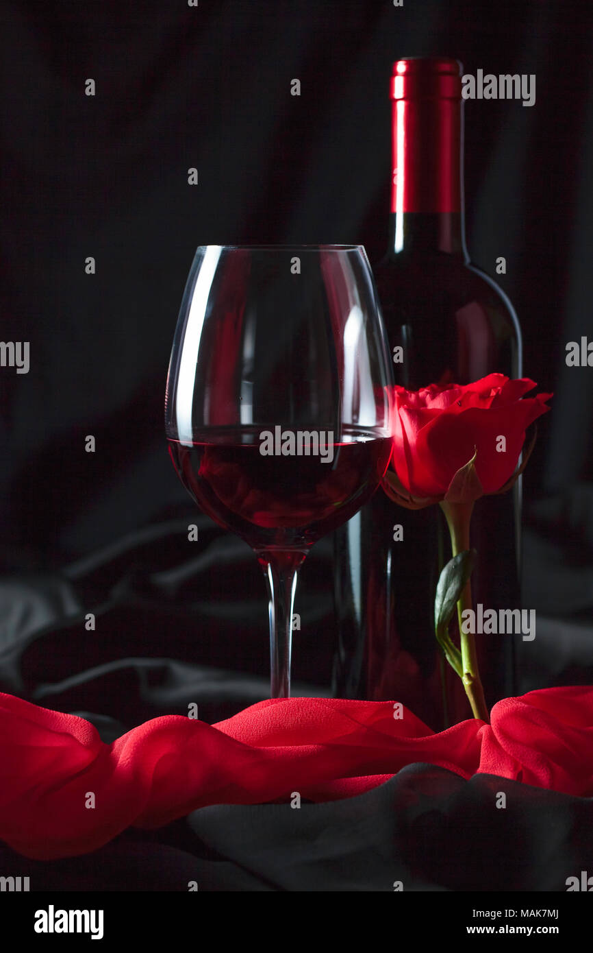 Bottle and glass of red wine with red silk and red rose on black background  Stock Photo - Alamy