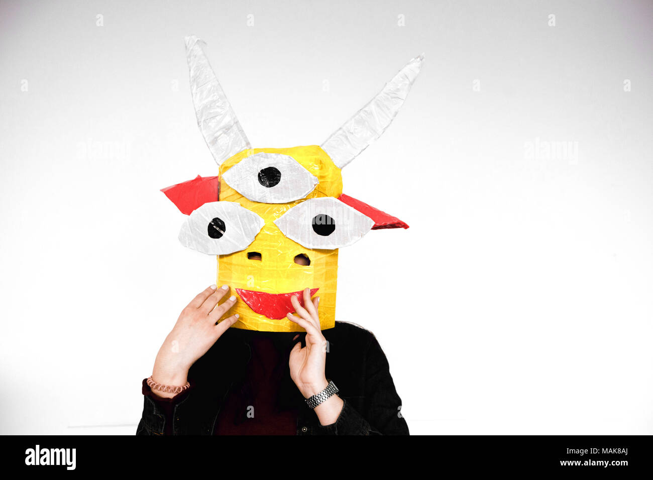 Unrecognizable person in yellow monster mask at white wall Stock Photo