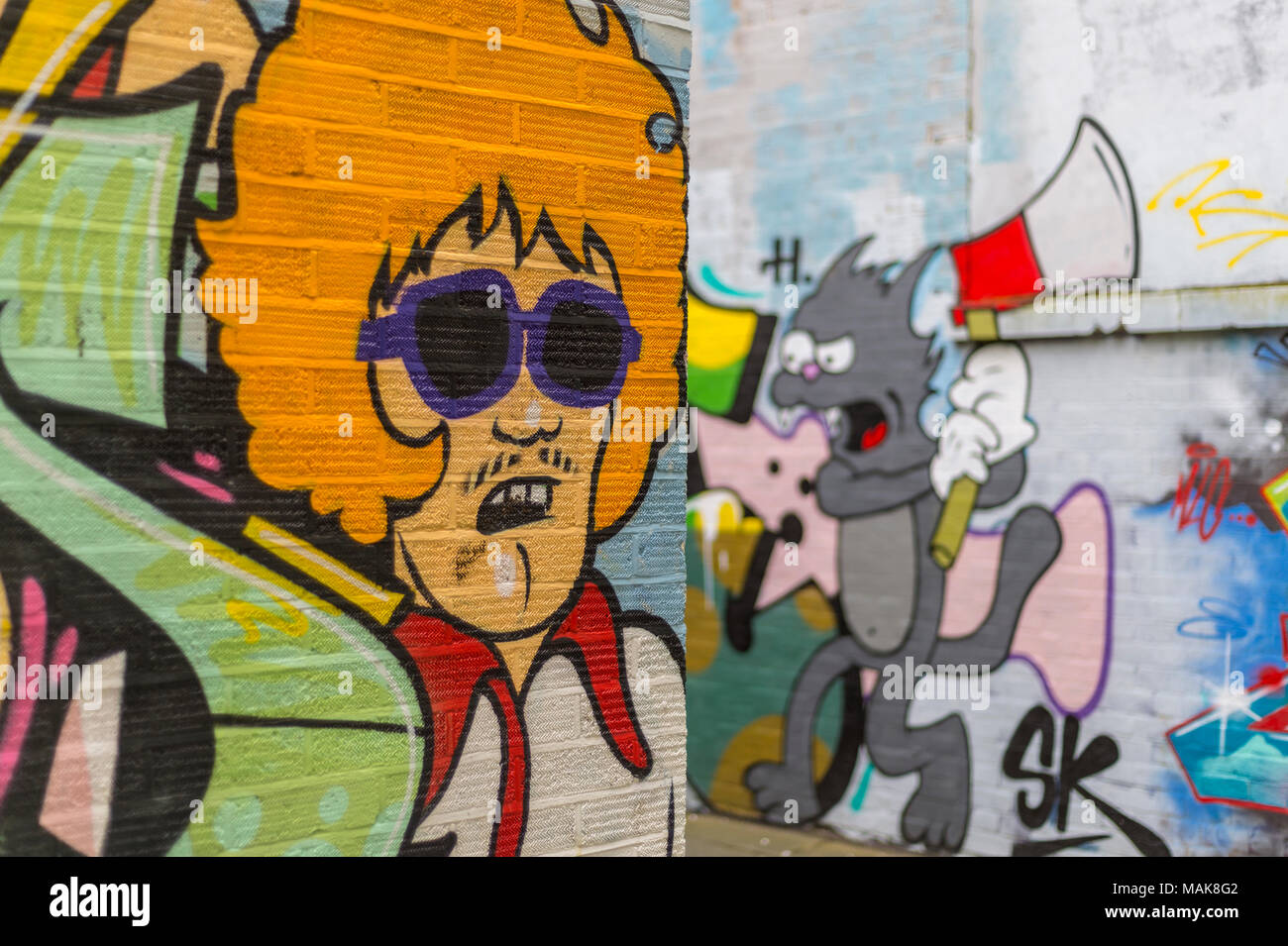 brick walls covered in cartoon graffiti and street art. Close up. Stock Photo