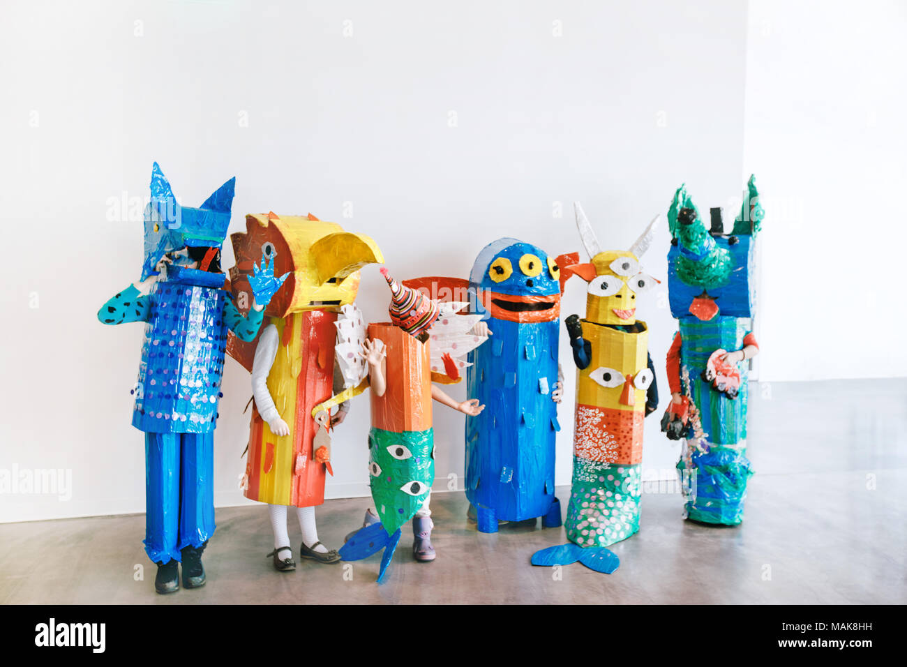 People in handmade colorful monsters costumes standing together in studio Stock Photo