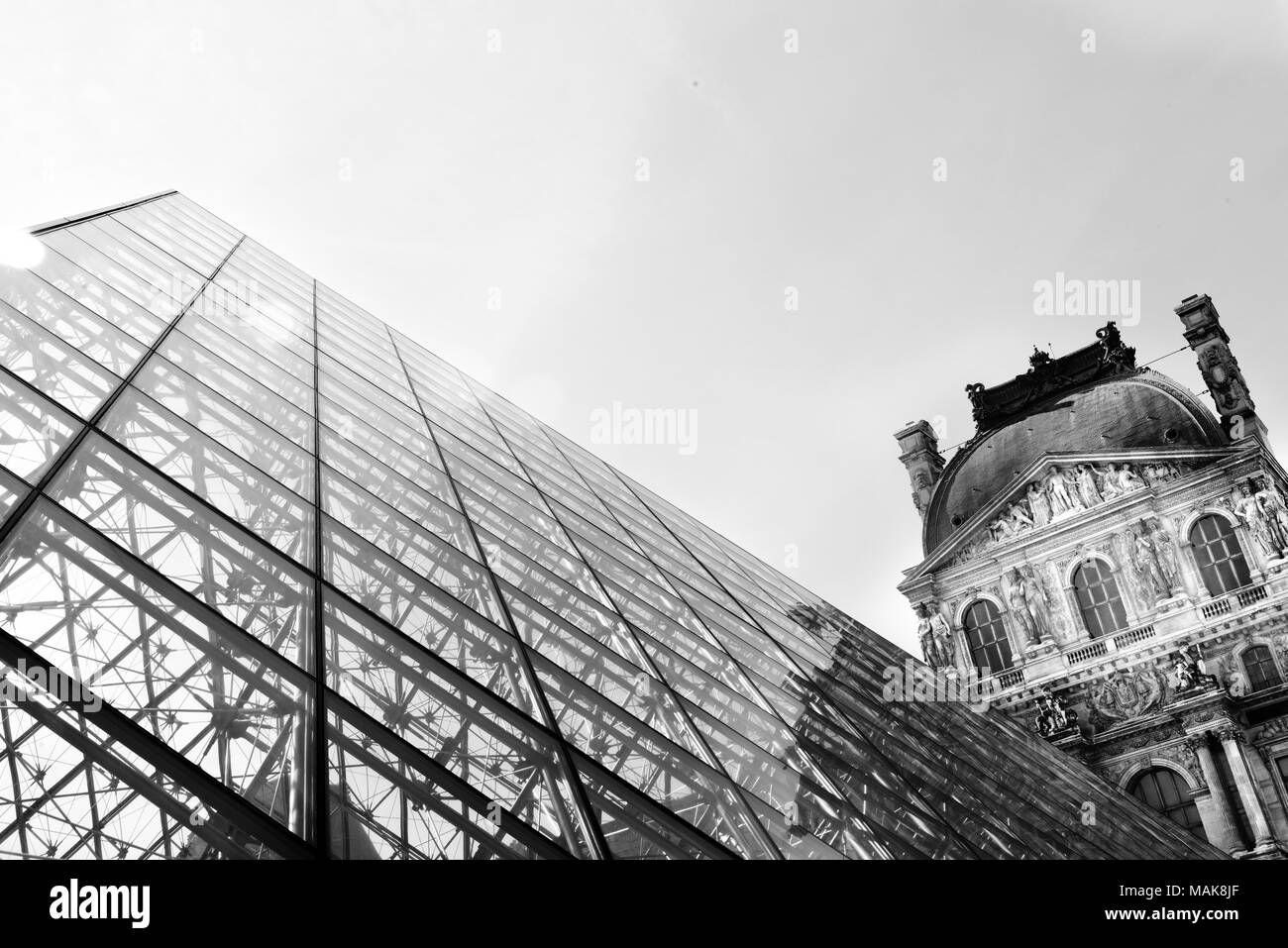 The glass pyramid of the Louvre and part of the Royal Palace in black and white Stock Photo