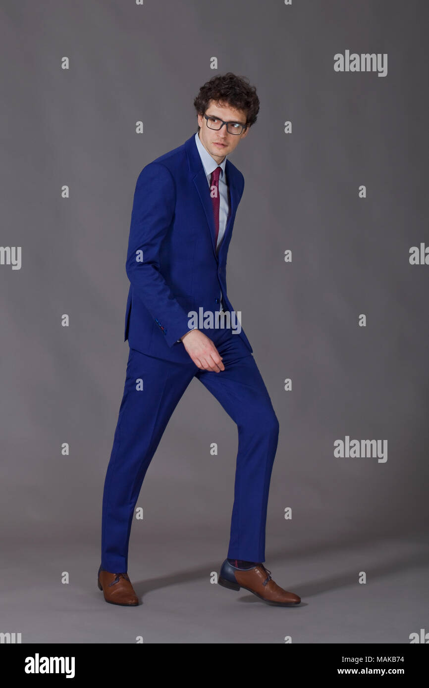 Curly man with glasses wearing in blue suit making step Stock Photo