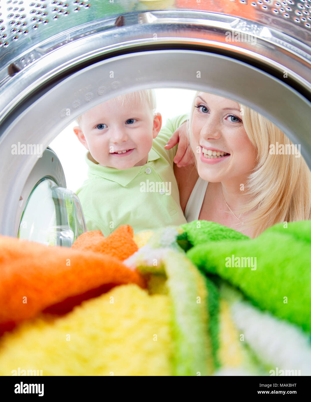 happy kid and mother looking inside wash machine with interest Stock Photo