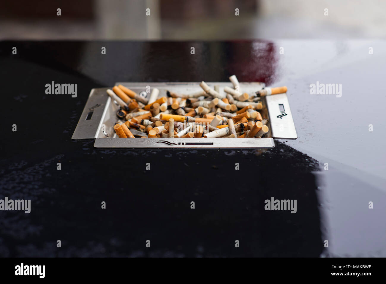 A full ashtray on top of a rubbish bin in the rain Stock Photo Alamy